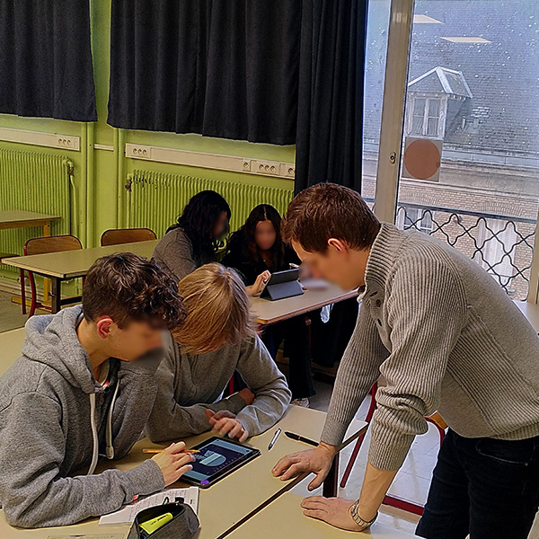 enseignant avec 2 binômes d'élèves sur tablettes